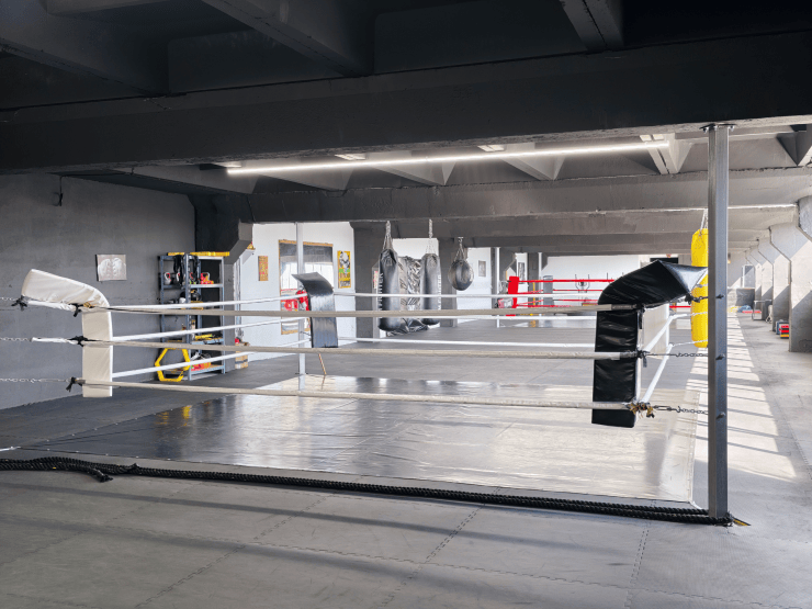 Colț de ring cu corzi albe și sac de box negru