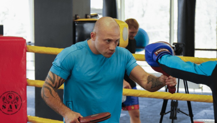 Antrenor de box lucrând la mănuși cu un sportiv în ring
