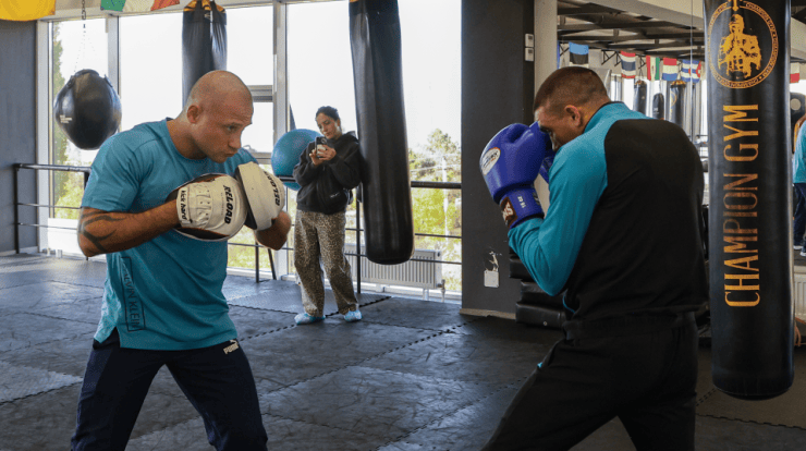 Doi boxeri la antrenament, lângă sacii de box